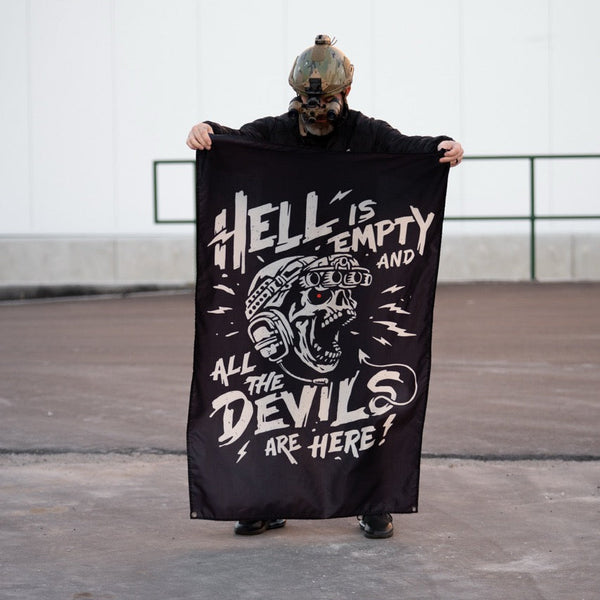Person in tactical gear holding Savage Tacticians flag with skull and bold graphic text