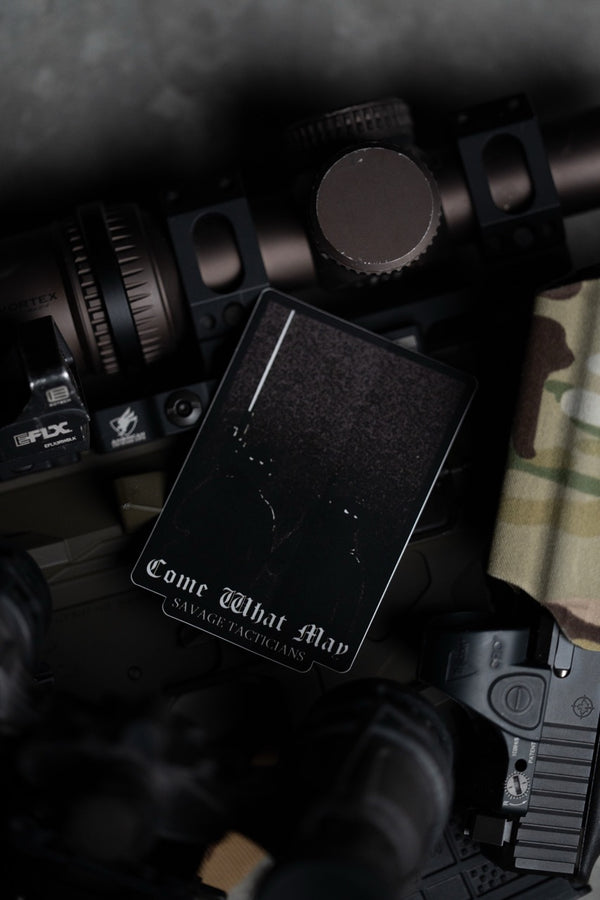 Savage Tacticians Come What May card on tactical rifle gear and camouflage fabric