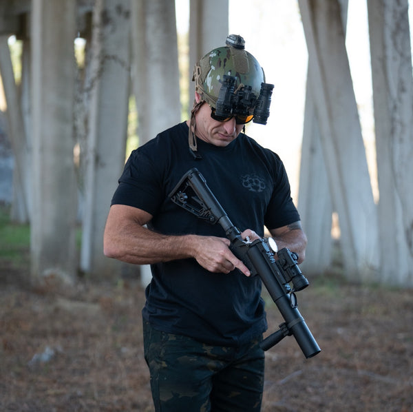 Person in tactical helmet with NODs wearing the Gangster tee holding a rifle in a urban setting