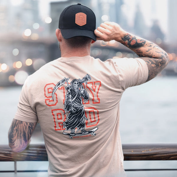 Savage Tacticians t-shirt with grim reaper graphic and STAY RAD text, worn by tattooed man