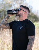 Tattooed man in sunglasses wearing Savage Tacticians shirt drinking from a black tumbler outdoors