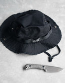 Savage Tacticians black boonie hat with SavTac logo and tactical knife on concrete