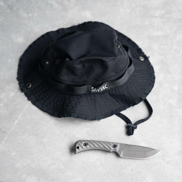 Savage Tacticians black boonie hat with SavTac logo and tactical knife on concrete