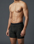 Male model in camo boxer briefs with Savage Tacticians logo waistband, gray background