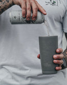 Tattooed man pouring drink into Savage Tacticians branded grey tumbler