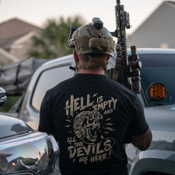 Man in tactical gear wearing Savage Tacticians shirt with bold graphic design and lettering