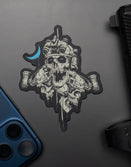Savage Tacticians skull sticker with night vision helmet on laptop, blue phone and handgun nearby