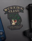 Savage Tacticians skull helmet sticker with 'Working Class' design on a laptop, next to a phone and firearm.