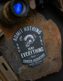 Savage Tacticians tactical sticker with skull helmet on stone, surrounded by gear