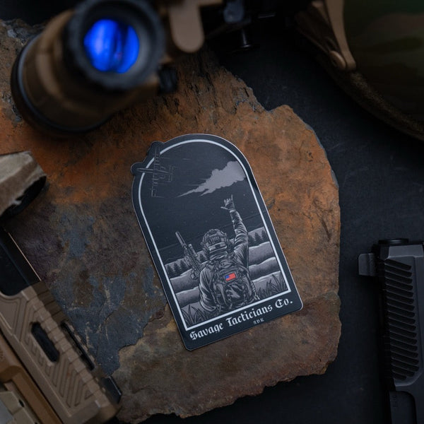 Savage Tacticians patch with soldier graphic on a rock, tactical gear nearby