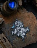 Savage Tacticians tactical skull sticker on rock with rifle accessories