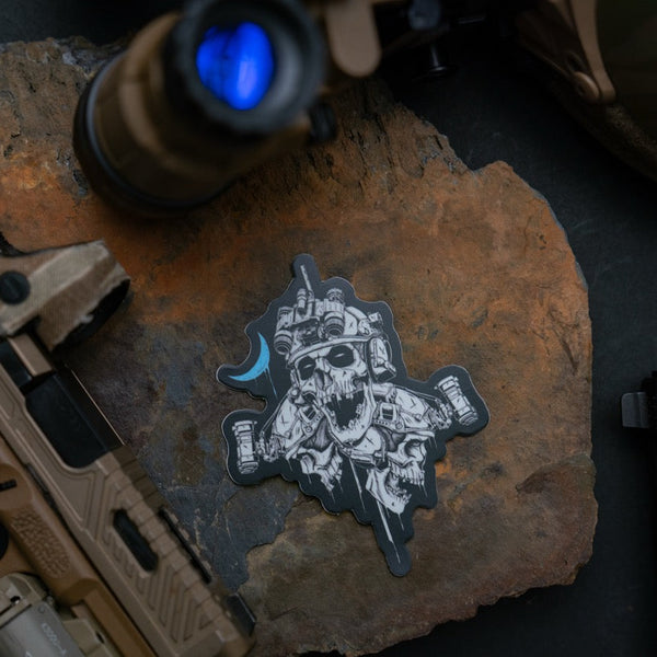 Savage Tacticians tactical skull sticker on rock with rifle accessories
