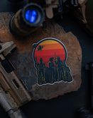 Savage Tacticians sticker with armed figures and sunset, surrounded by tactical gear