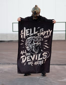Person in tactical gear holding Savage Tacticians flag with skull and bold graphic text