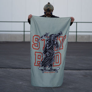 Person with tactical helmet holds Savage Tacticians Stay Rad flag featuring Grim Reaper graphic.