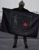 Person in tactical gear holding Savage Tacticians flag with skeleton and heart graphic.