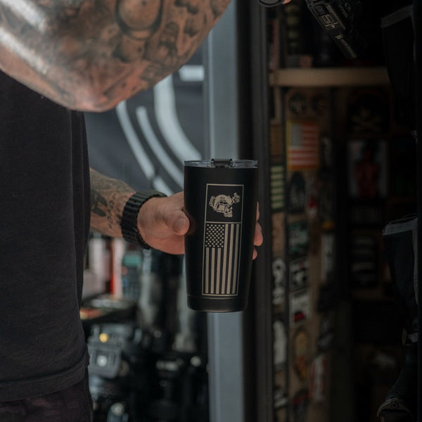 Tattooed man holding Savage Tacticians black tumbler with American flag and rhino design