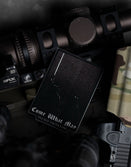 Savage Tacticians Come What May card on tactical rifle gear and camouflage fabric