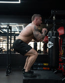Man wearing Savage Tacticians shorts doing box jumps in a gym with punching bags