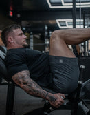 Man lifting weights in gym wearing Savage Tacticians athletic shorts and black shirt