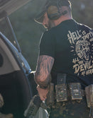 Man in Savage Tacticians tactical t-shirt with skull graphic, gear belt, outdoors
