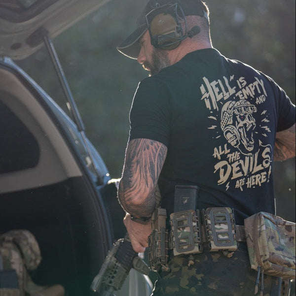 Man in Savage Tacticians tactical t-shirt with skull graphic, gear belt, outdoors