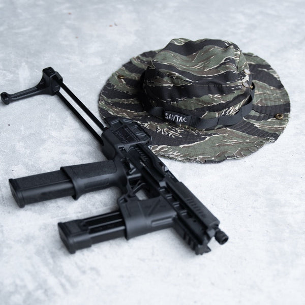 Savage Tacticians camo boonie hat with SAVTAC patch and tactical rifle on concrete