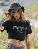 Woman in Savage Tacticians camo bucket hat and black graphic crop top outdoors