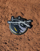 Savage Tacticians A-10 jet sticker with F-BOMB text on a textured brown surface