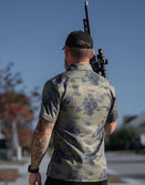 Savage Tacticians camo shirt with tropical print, man holding rifle outdoors