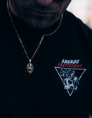 Person wearing a black t-shirt with 'Savage Tacticians' logo and a necklace with a pendant.