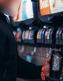 Person filling a Savage Tacticians tumbler at a soda fountain, wearing black hoodie and orange watch