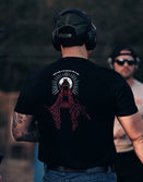 Savage Tacticians black t-shirt with red graphic design, worn by man outdoors at range
