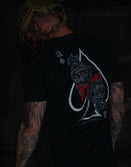 Tattooed man in tactical helmet wearing Savage Tacticians black graphic t-shirt with skull art
