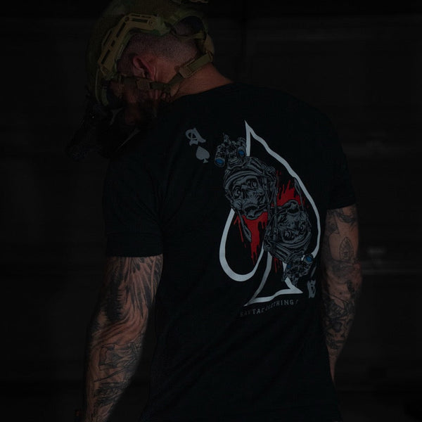 Tattooed man in tactical helmet wearing Savage Tacticians black graphic t-shirt with skull art