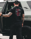 Savage Tacticians tattooed man wearing black graphic t-shirt next to TRD Off Road SUV